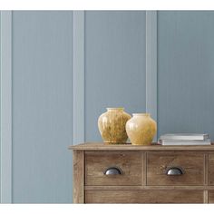 two vases sitting on top of a wooden dresser