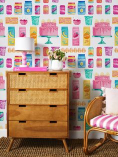 a dresser and chair in front of a colorful wallpaper