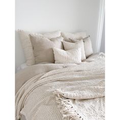 an unmade bed with white linens and pillows