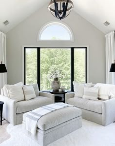 a living room with two couches and a coffee table in front of a large window