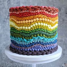 a multicolored cake is sitting on a white table and it's made out of knitted fabric