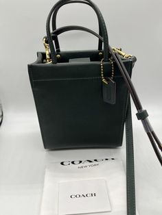 A buttery soft glovetanned leather mini tote based on the iconic "Cashin Carry" from 1969. Perfect for night outs! Coach Mini Cashin Tote color: amazon green glovetanned leather one credit card slot magnetic snap closure, fabric lining handles with 3" drop detachable strap with 21 1/2" drop for shoulder or crossbody wear four protective feet at base style: C4828Measures 5 1/2" (L) x 6 1/2" (H) x 3" (W) All products sold on suzishop are guaranteed to be authentic. Sale items are purchased directly from authorized dealers or respected industry wholesalers or distributors. Items are never refurbished, factory seconds, or replicas. Brand new, never used, with tag. Not considering offers. Item on hand and ready to ship. Will ship within one business day of received payment. Buyer pays for shipp Green Leather Bag With Snap Closure, Green Style, Pet Home, Mini Tote, Leather Mini, Green Fashion, Snap Closure, Sale Items, Bags Handbags