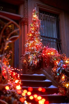 a lit christmas tree sitting on top of a set of stairs