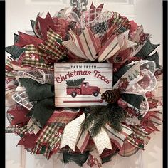 a christmas wreath is hanging on the front door with a book about christmas trees in it