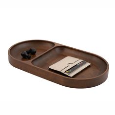 a wooden tray with two compartments and a notepad on it, next to an earbuds