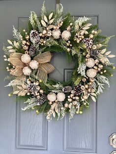 a wreath with pine cones, berries and greenery is hanging on the front door