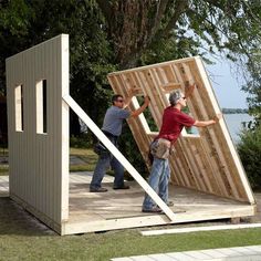 two men are building a house out of wooden planks and plywood with their hands