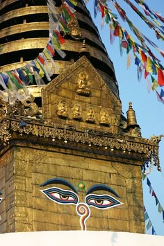 the top of a building with many colorful flags flying in the air above it and an ornately decorated tower