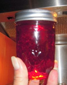 a person holding a jar filled with red liquid