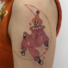 a woman with a tattoo on her arm that has a drawing of a clown in it