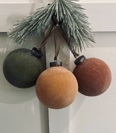 three ornaments hanging on the wall next to a pine cone and fir tree ornament