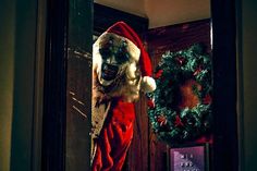 a creepy santa clause is standing in front of a door with a wreath on it