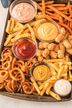 a tray filled with different types of food and dipping sauces on top of them