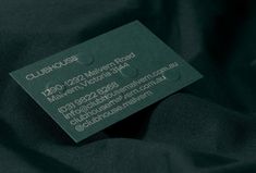 a close up of a business card on a black fabric material that is very dark green