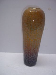 a brown and black vase sitting on top of a white table next to a wall