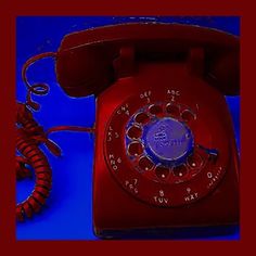 an old red telephone sitting on top of a blue table next to a phone cord