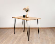 a wooden table with hairpin legs and a vase on top