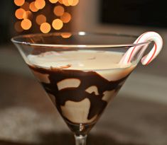 a chocolate martini with candy canes in it on a table next to a christmas ornament