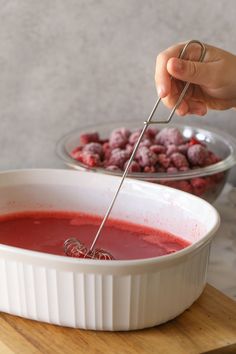 a bowl of red soup being stirred with a whisk by a ladle