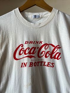 "1950s Coca Cola T-shirt. Has some staining on the front and the back, please refer to photos.  15.5\" Pit to Pit  25.5\" Length All sales final please ask any questions before buying - Thank you!" Vintage Coke Shirt, Vintage White T-shirt With Letter Print, Retro Cotton T-shirt Made In Usa, Vintage Pre-washed Cotton T-shirt, Vintage Crew Neck T-shirt With Screen Print, Vintage Crew Neck T-shirt With Letter Print, Vintage Red Top With Letter Print, Vintage Red Tops With Letter Print, Vintage Cotton T-shirt With Vintage Print