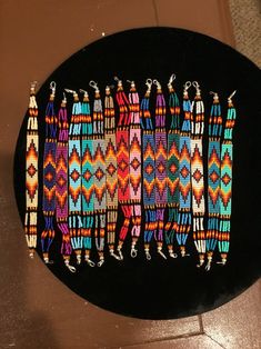 a group of beaded bracelets sitting on top of a black table next to a wall