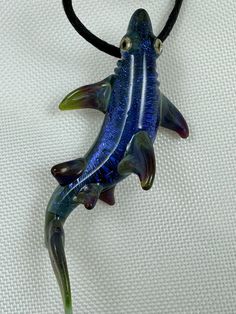 a blue and green glass fish on a black cord