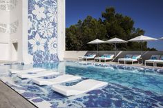 an empty swimming pool with lounge chairs and umbrellas next to the side of it