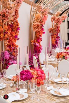 the table is set with white and gold plates, silverware, and pink flowers