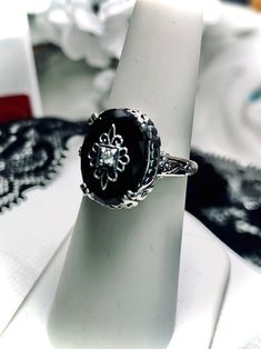 Simulated Onyx Black Sterling Silver RingEdward Design#D70e This filigree ring is an Edwardian antique reproduction in sterling silver. The beautiful, simulated onyx gemstone has delicate sterling silver embellishment. Set in the middle of the intricate design is a 1mm gem. Choose between a white cubic zirconia (CZ), lab created Moissanite, or genuine diamond. This oval gemstone is 14mm x 10mm. This ring sits 7mm off the finger. The inside of the band is marked 925 for sterling silver. Notice th Ornate Black Wedding Ring, Ornate Black Oval Ring, Ornate Round Ring With Stone Setting, Elegant Engraved Wedding Ring With Stone Setting, Elegant Wedding Engraved Ring With Stone Setting, Antique Filigree, Onyx Crystal, Edwardian Jewelry, Gem Diamonds