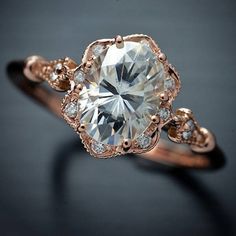 an engagement ring with a large diamond surrounded by small white and rose gold accents, on a black background