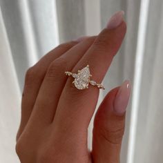 a woman's hand holding an engagement ring with two pear shaped diamonds on it