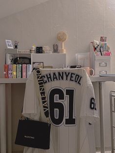 a baseball jersey is hanging on a desk in a room filled with books and other items