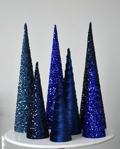 three blue christmas trees sitting on top of a white table