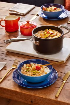 two bowls of food sit on a table with utensils and silverware next to them