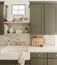 a kitchen with gray cabinets and white counter tops, an open shelf above the sink