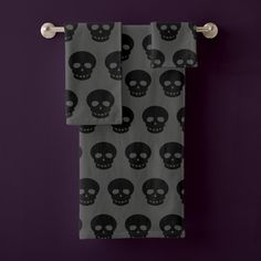 two towels with black skulls on them hanging from the wall in front of a purple background