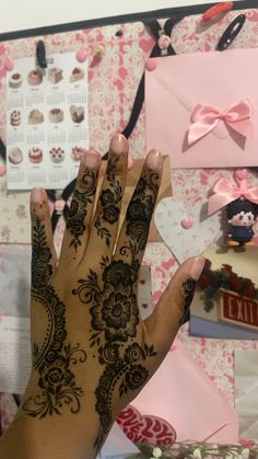 a woman's hand with henna on it and pink flowers in the background