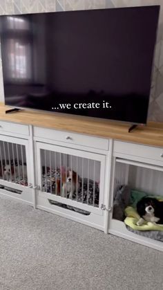 a flat screen tv sitting on top of a wooden shelf next to two white dog kennels