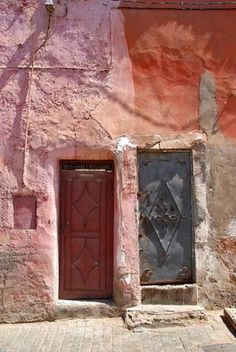 an old building with a red door and brick sidewalk