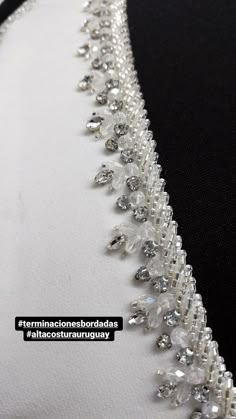 a close up view of the beading on a white dress with black trimming