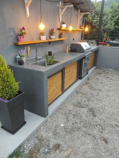 an outdoor kitchen with potted plants on the counter and grill area in the back