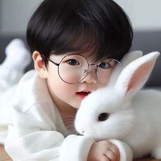 a little boy with glasses holding a white bunny