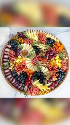 a platter filled with lots of different types of fruits and veggies on top of a marble counter