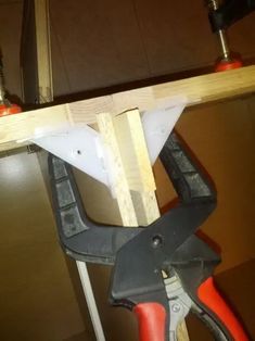 a pair of pliers are attached to the top of a piece of wood that is being worked on