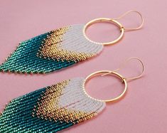 two pairs of beaded earrings with gold hoops on a pink surface, one is green and the other is white