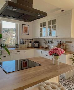 a kitchen with a stove top oven sitting next to a counter and flowers in a vase