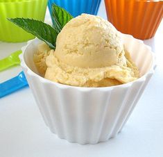 a bowl filled with ice cream next to cupcakes