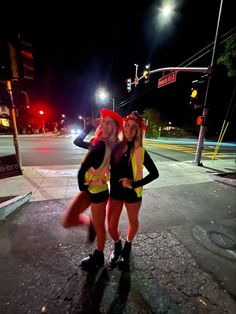 two women dressed in costumes standing on the street at night with their arms around each other