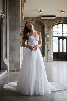 a woman in a white wedding dress posing for the camera with her hands on her hips