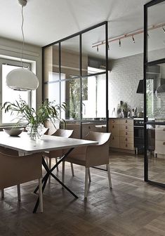 a table and chairs in a room with wooden flooring, glass walls and large windows